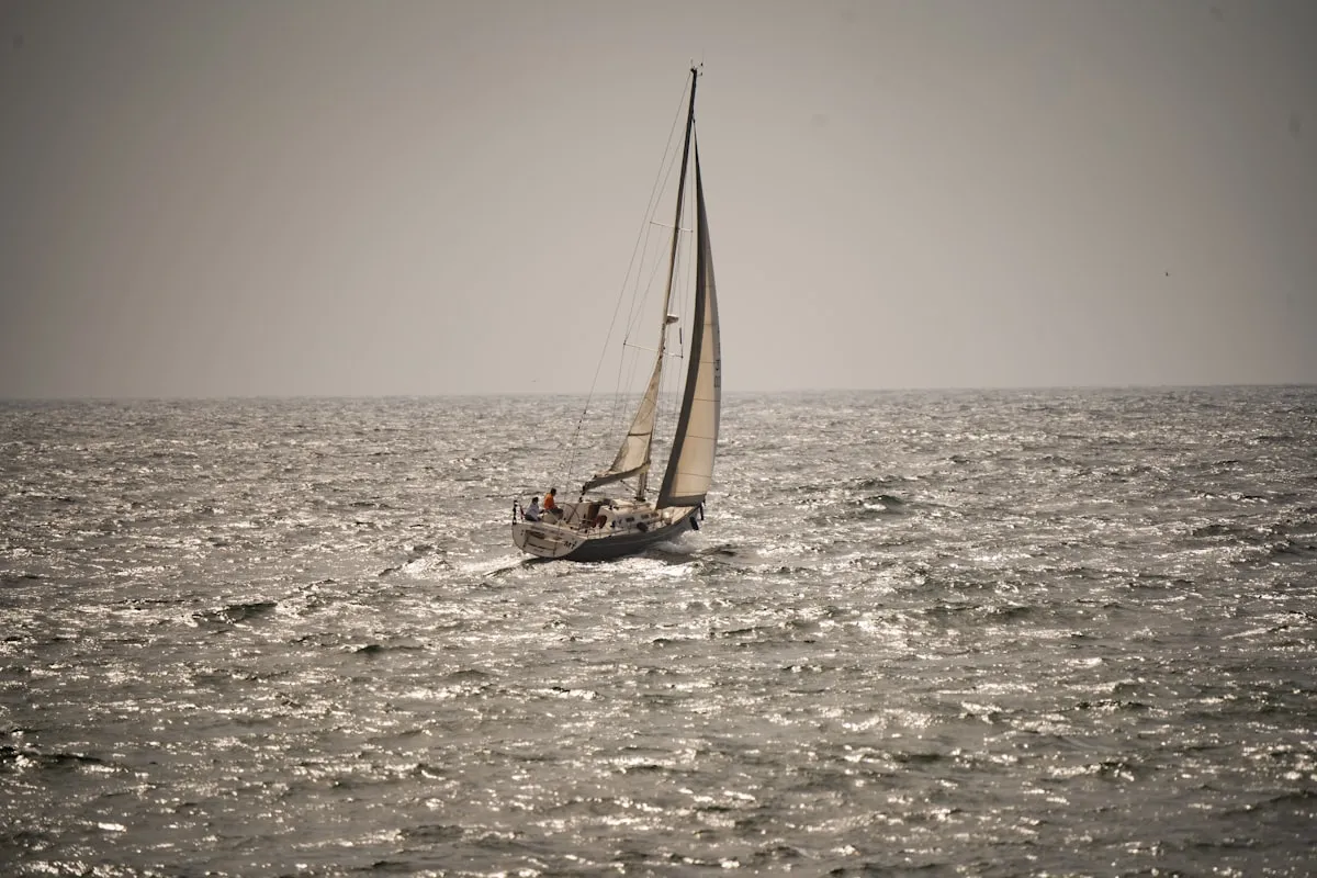 Sailboat sailing across calm water surrounded by nature